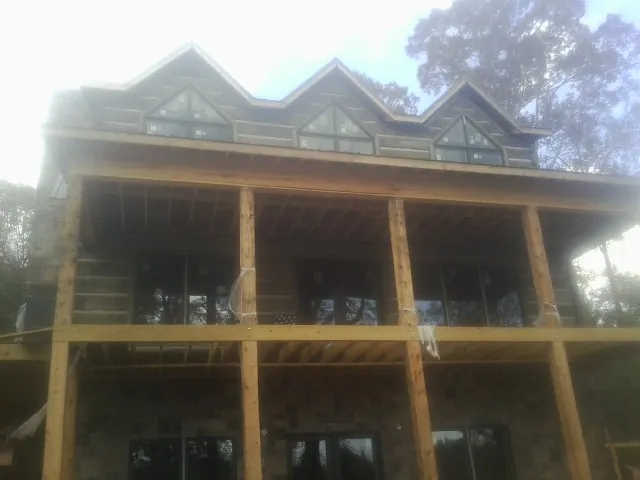 Dormers and porch framing on a large log home under construction — Roof Coating work by our crew in Santa Fe